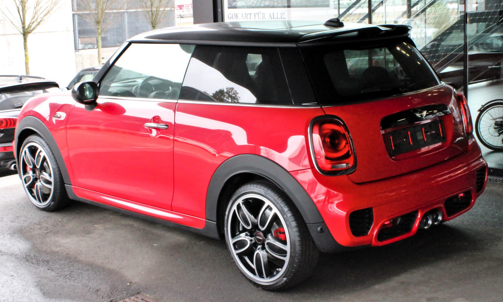 Rear side view of red Mini Hatch with black roof and alloy wheels