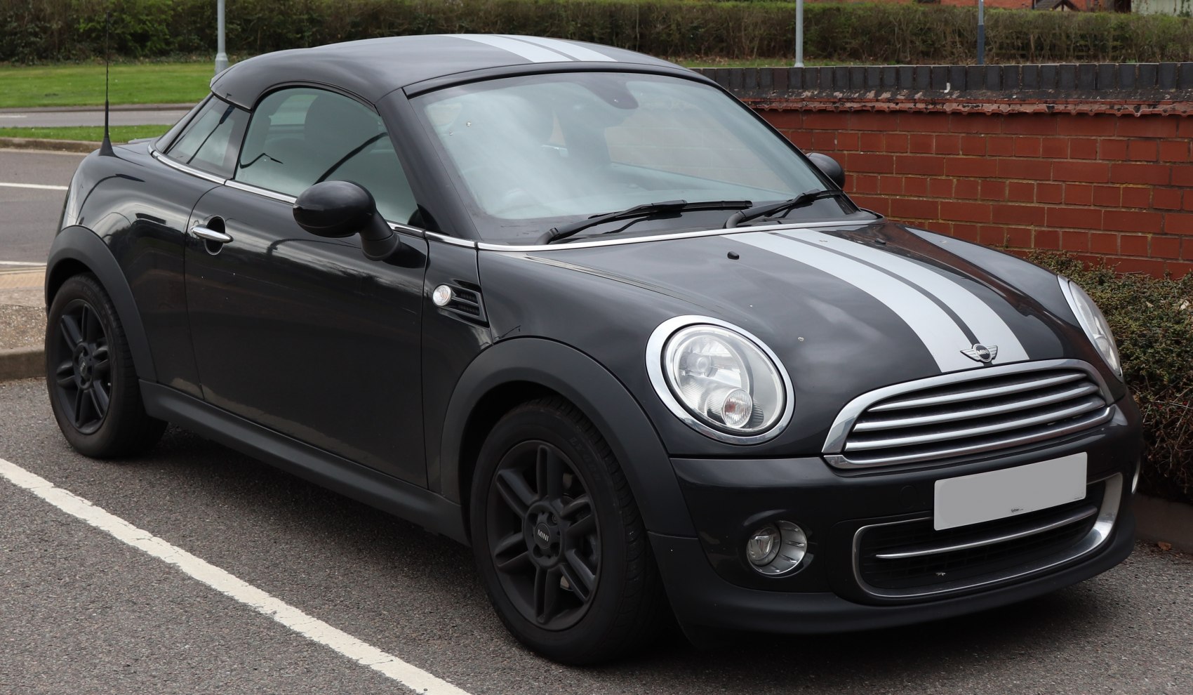 Front-side view of black compact coupe with racing stripes and round headlights