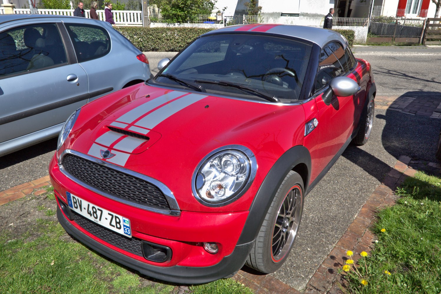 Red compact coupe with silver racing stripes and hood scoop front view