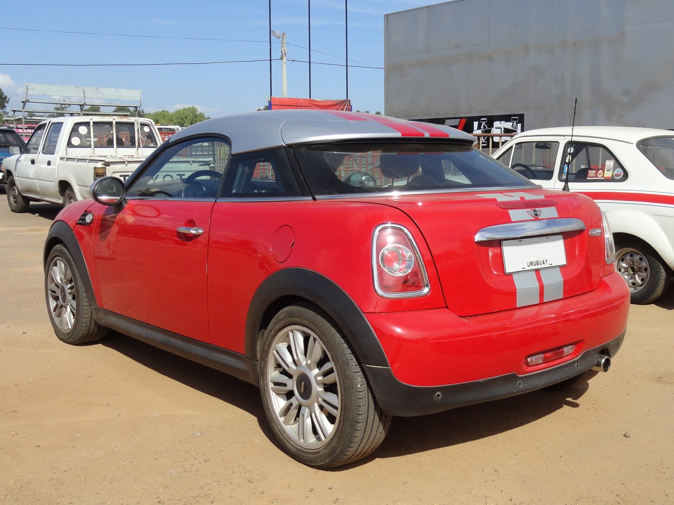 Rear side of a red two-door compact coupe with silver top and racing stripes