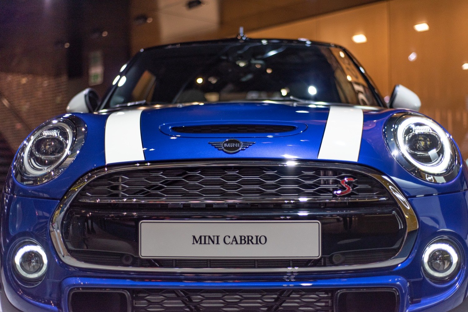 Close-up of front grille, headlights, and white stripes on blue Mini Convertible.