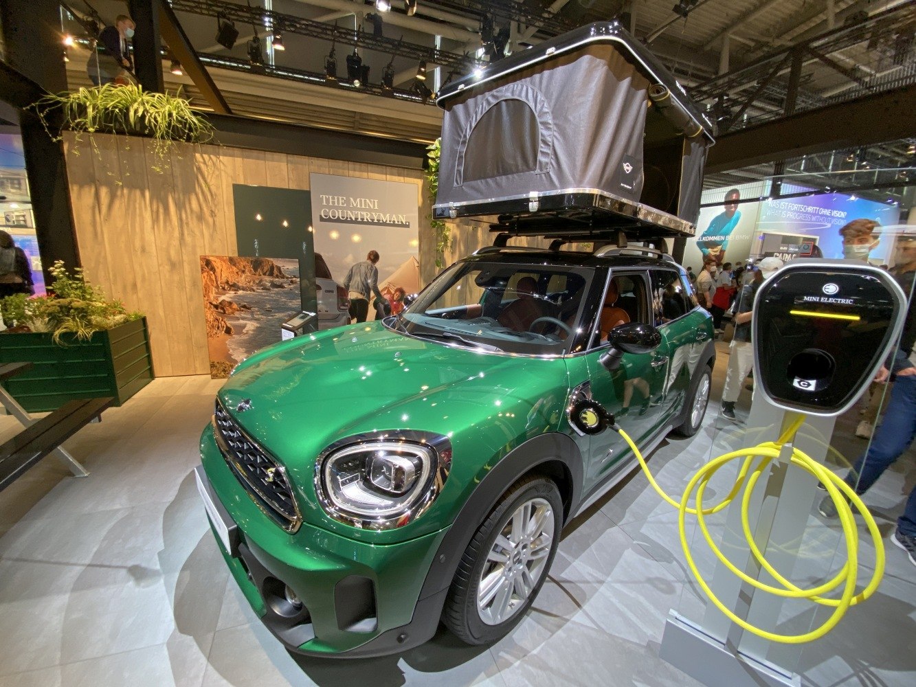Green compact SUV with roof tent and electric charging cable