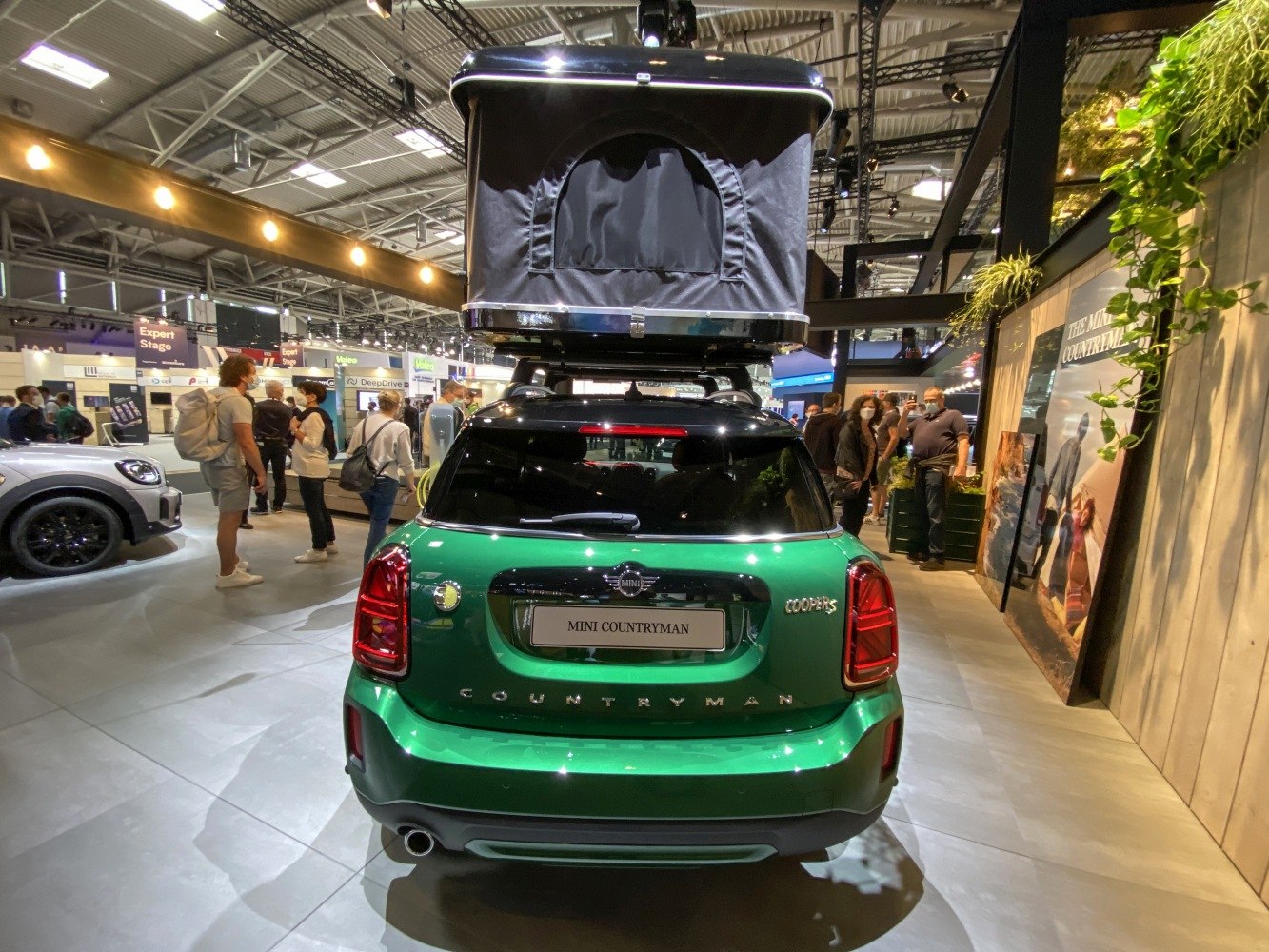 Rear view of green compact SUV with rooftop tent at exhibition