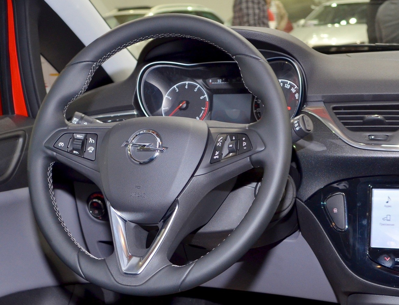 Steering wheel with control buttons and dashboard instrument cluster.
