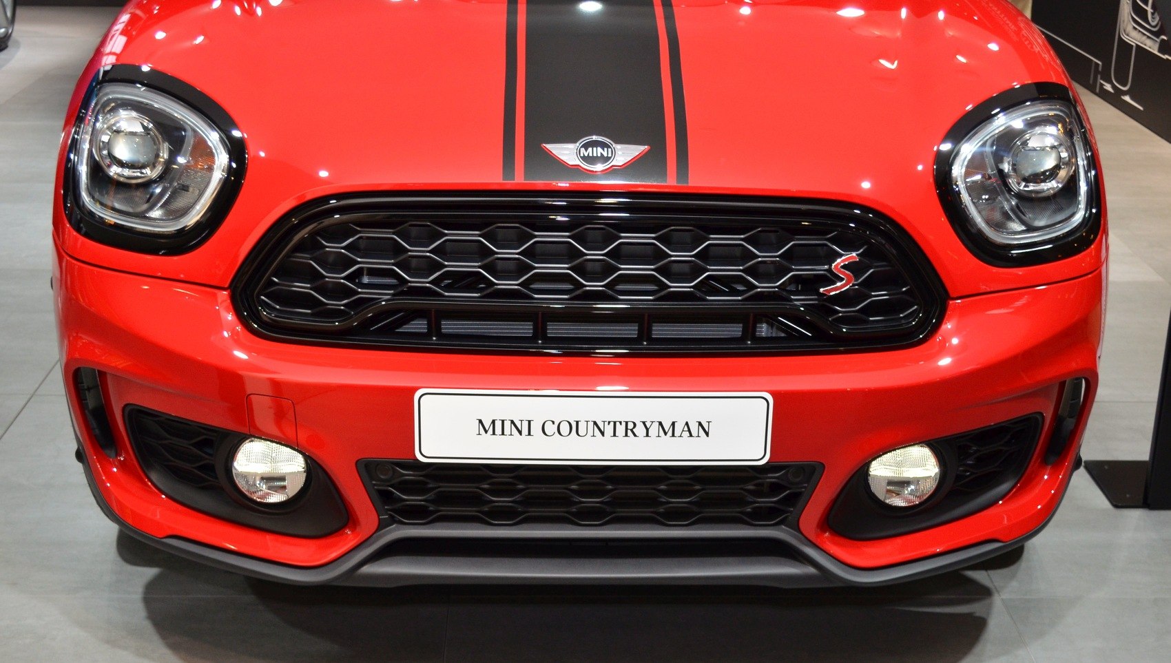 Hexagonal grille, distinctive headlights, fog lights on red car front.