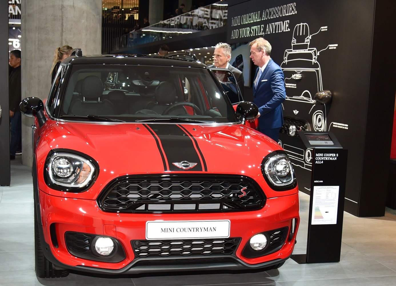 Red car front with black grille, headlights, fog lights, and dual hood stripes
