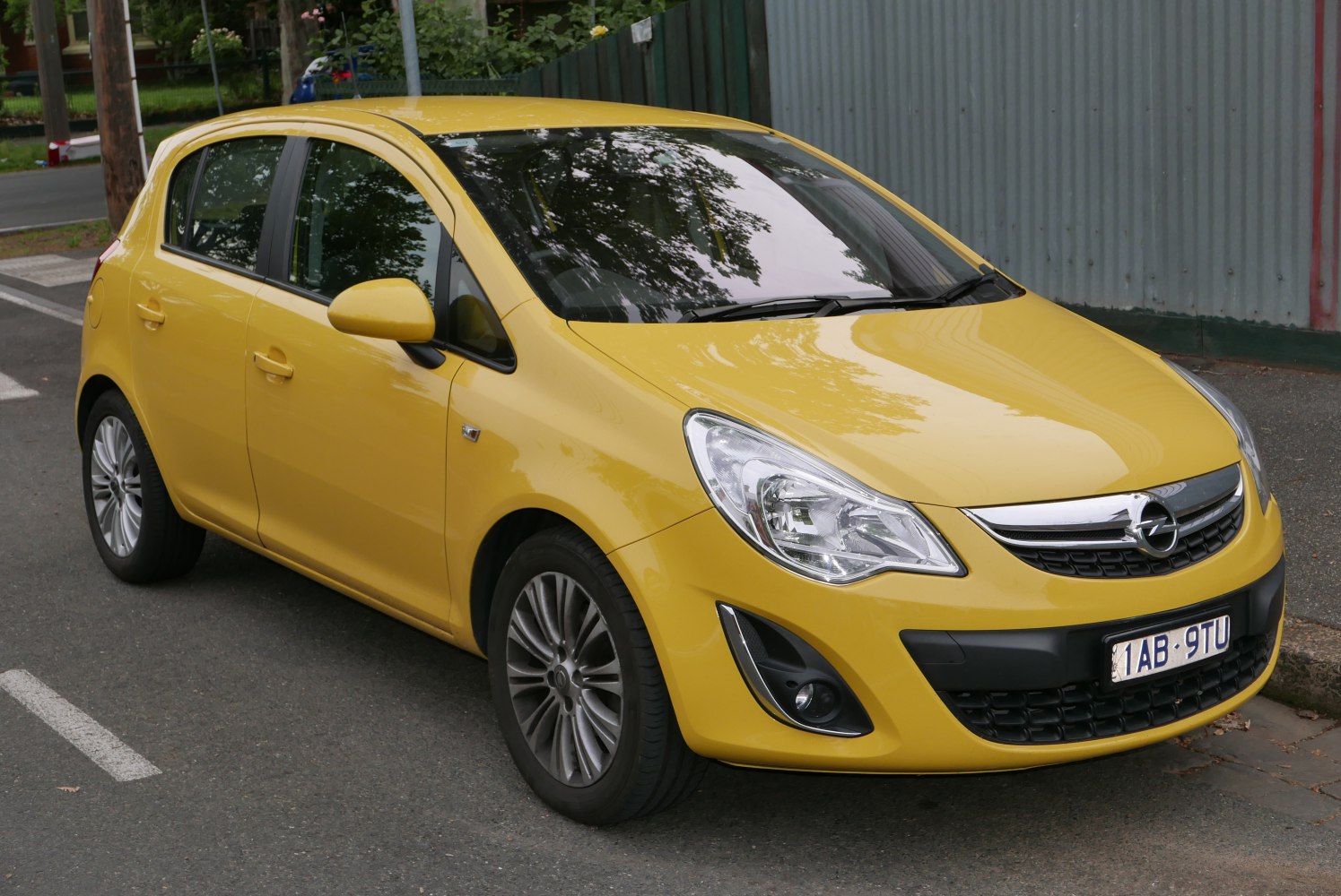 Yellow compact 5-door hatchback front side view with headlights and grille