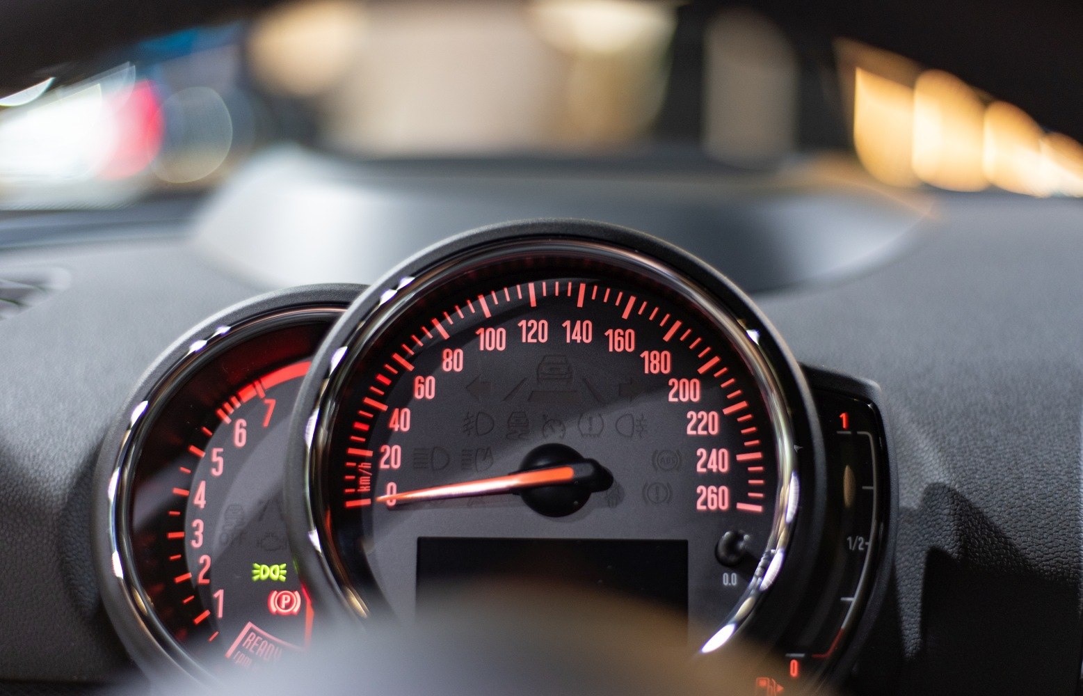 Close-up of dashboard speedometer and tachometer with red illumination