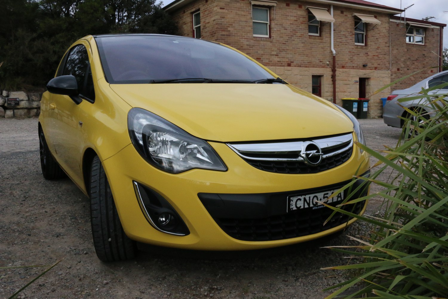 Front view of yellow compact 3-door hatchback with headlights and grille