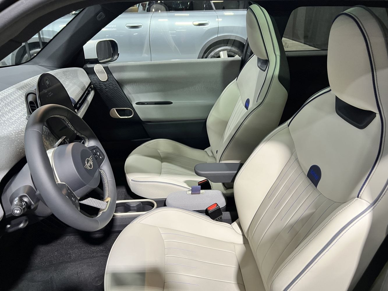 Modern dashboard and white leather seats with blue accents.