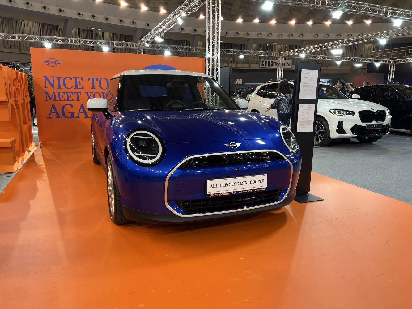 Front view of a blue electric hatchback with round LED headlights and a modern grille.