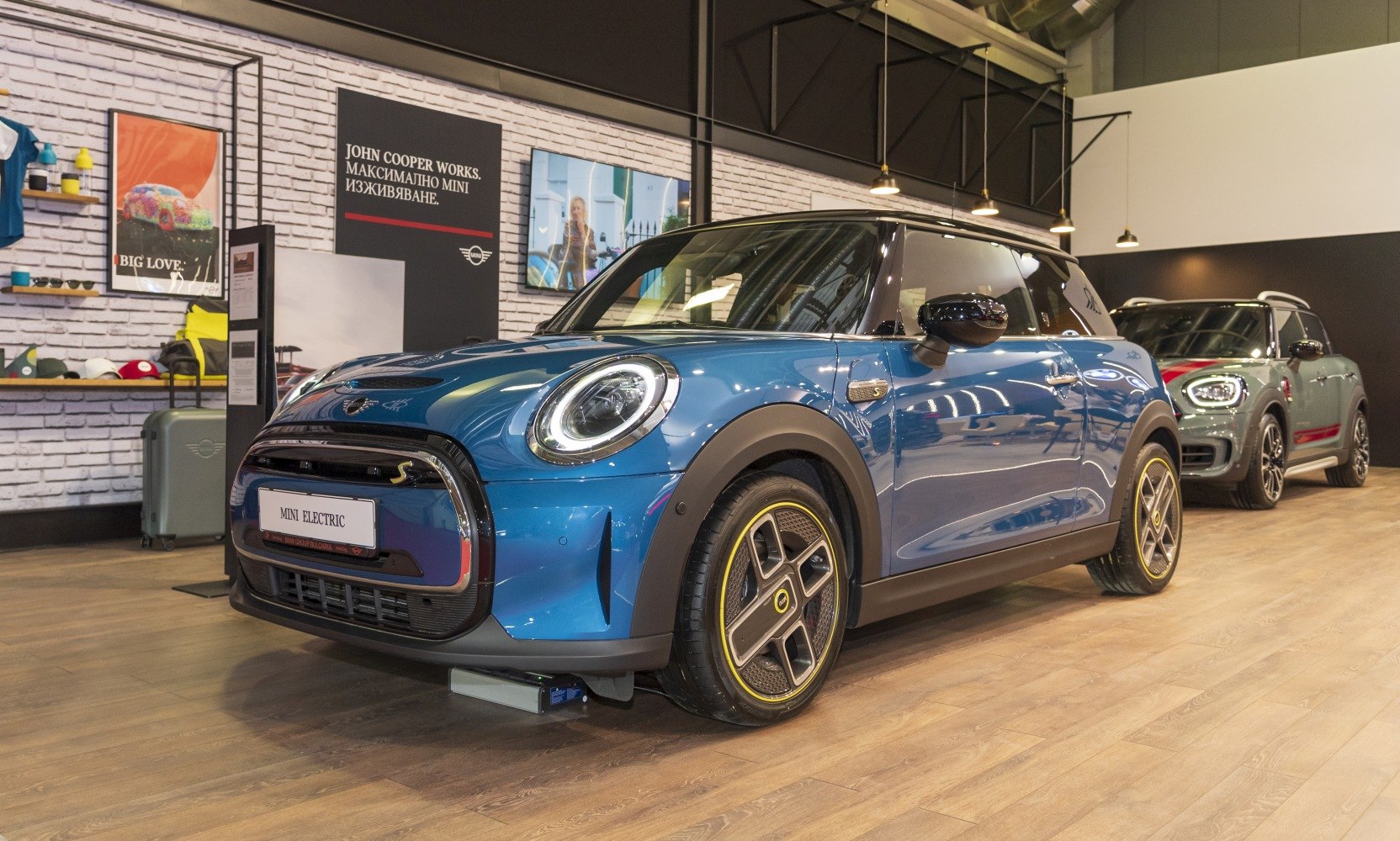 Front and side view of a blue electric compact car with distinctive LED headlights and patterned alloy wheels