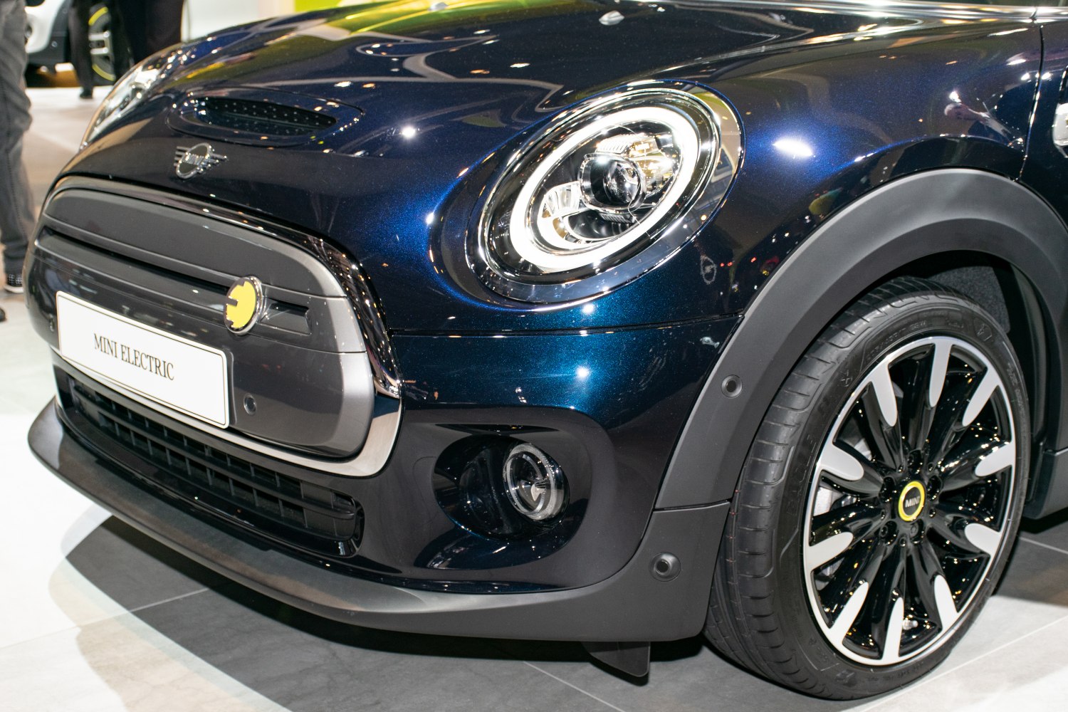 Front close-up of LED headlights, grille, and wheel of electric Mini.