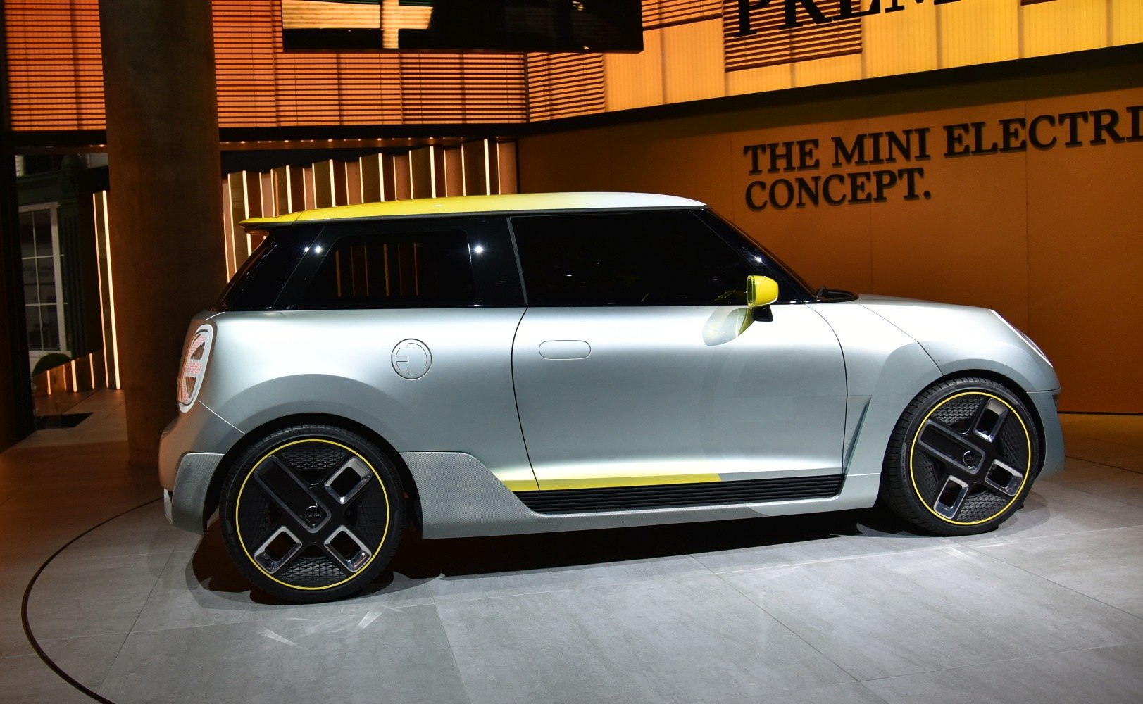 Side view of electric hatchback with futuristic multi-spoke wheels and yellow accents