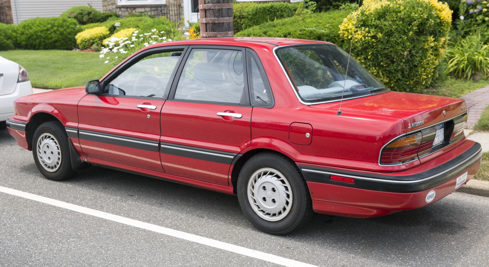 Side and rear view of red vintage sedan with distinctive rear lights and hubcaps