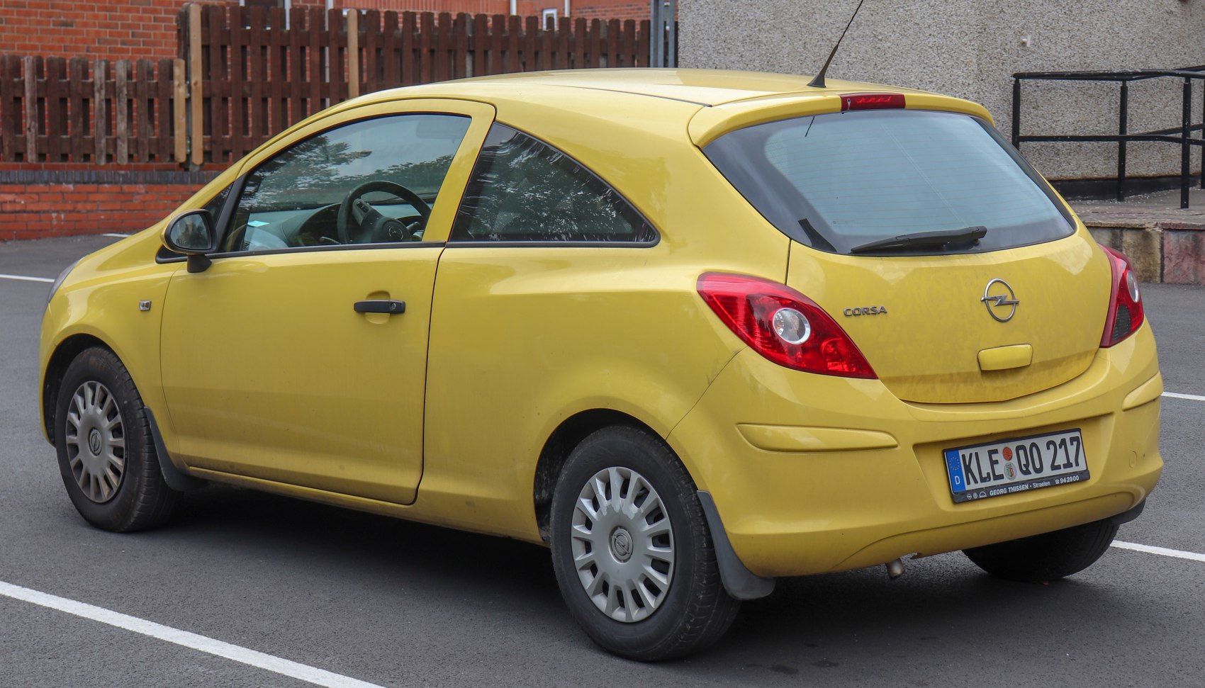 Rear side view of a yellow 3-door hatchback with distinct taillights and compact body.