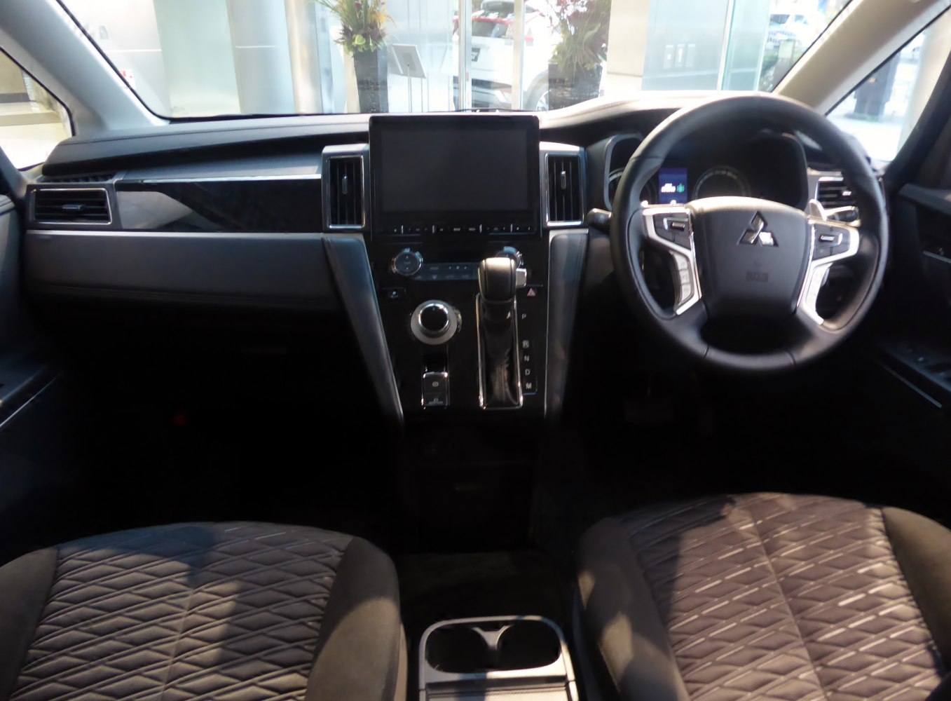 Modern dashboard with central touchscreen and multifunction steering wheel in vehicle interior.