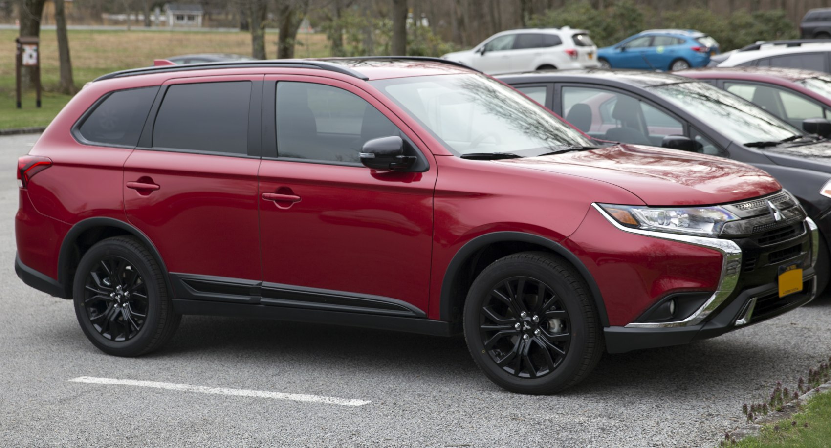 Red SUV with black wheels and chrome-accented grille side front view