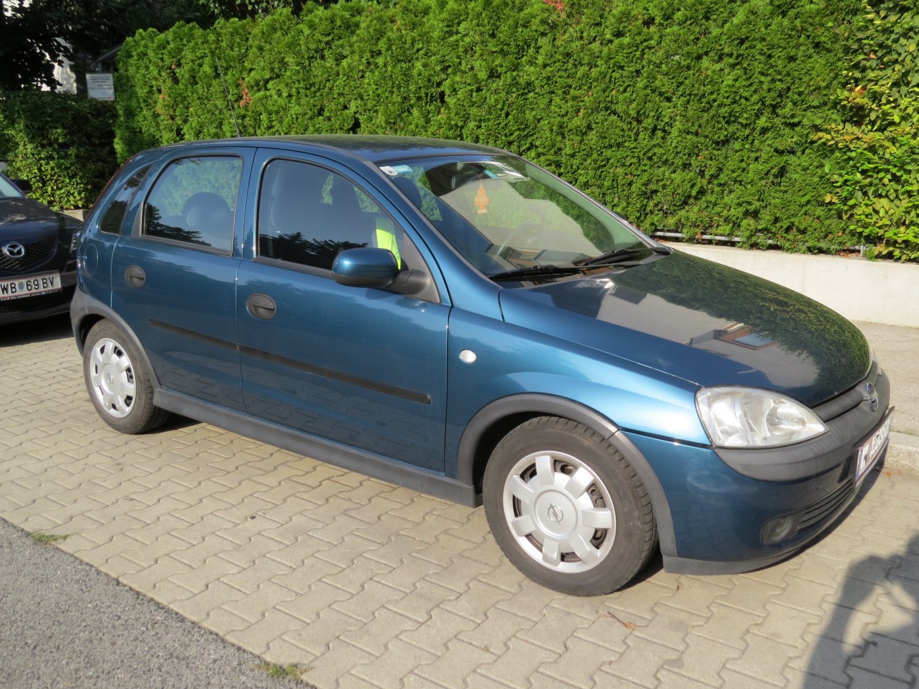 Side profile of a compact blue five-door hatchback with rounded headlights