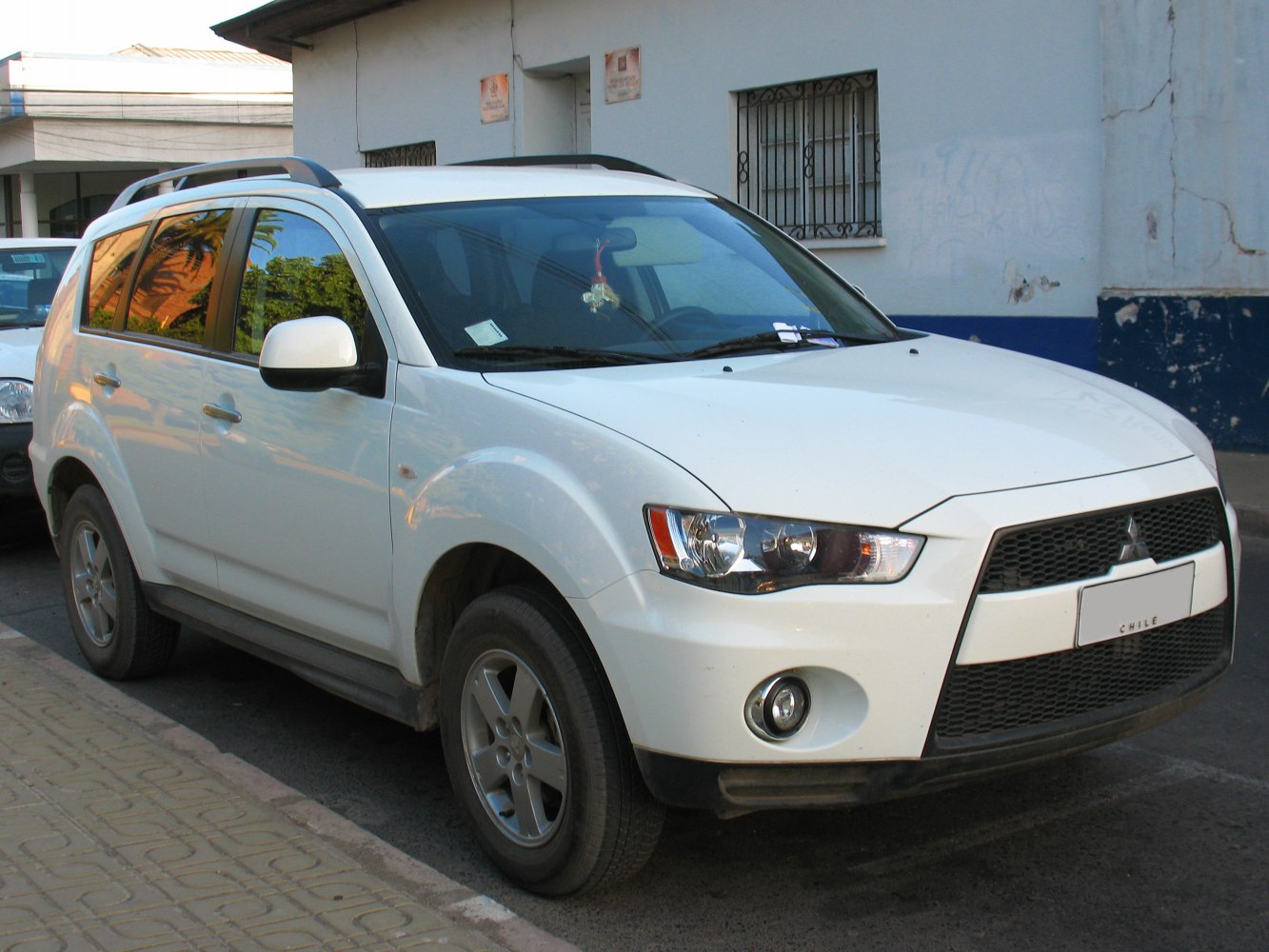 White SUV with bold front grille, fog lights, and roof rails