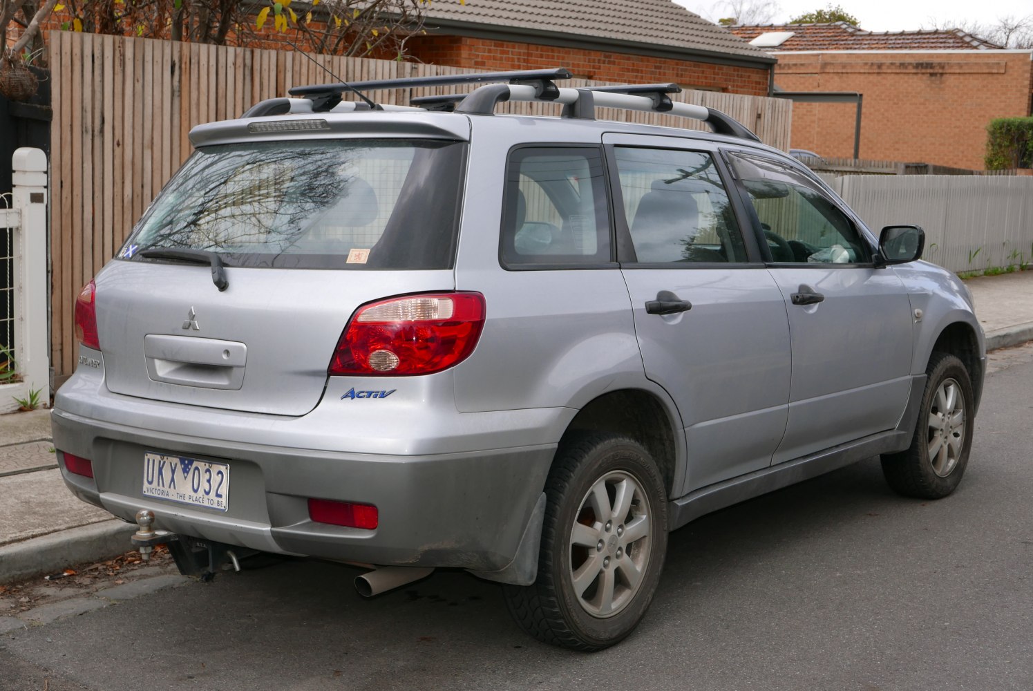Rear side view of silver SUV with roof rails and tow hitch