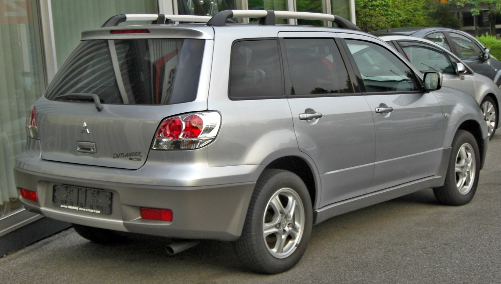 Silver SUV with roof rails, rear spoiler, and five-spoke wheels