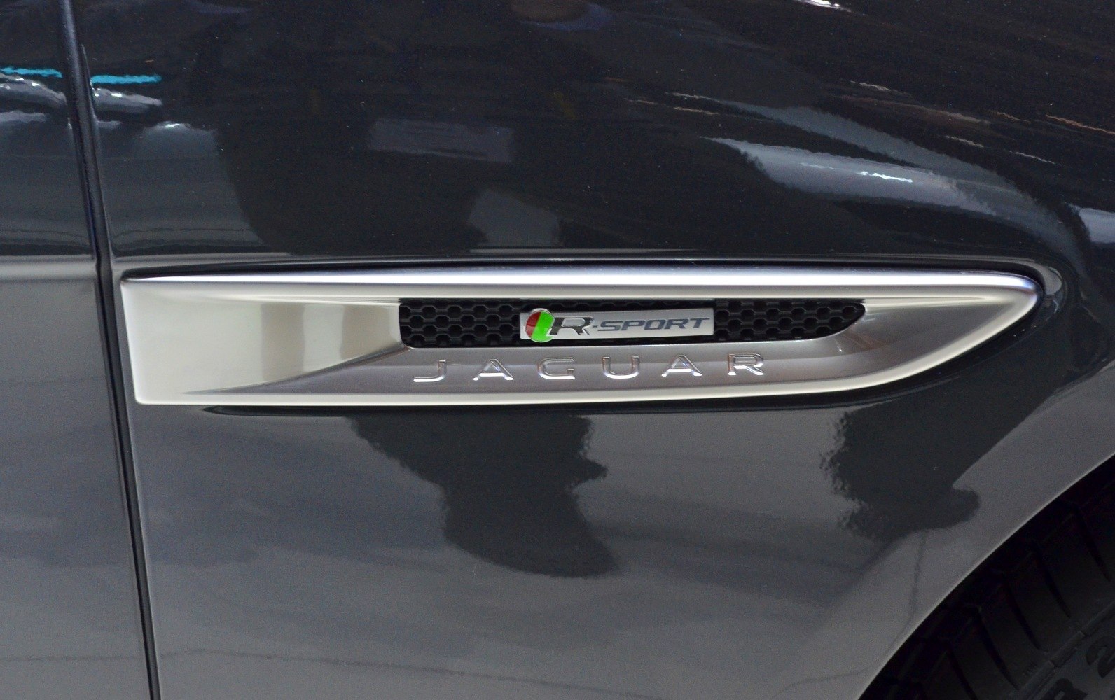 R-Sport side vent with chrome trim and logo on dark vehicle body