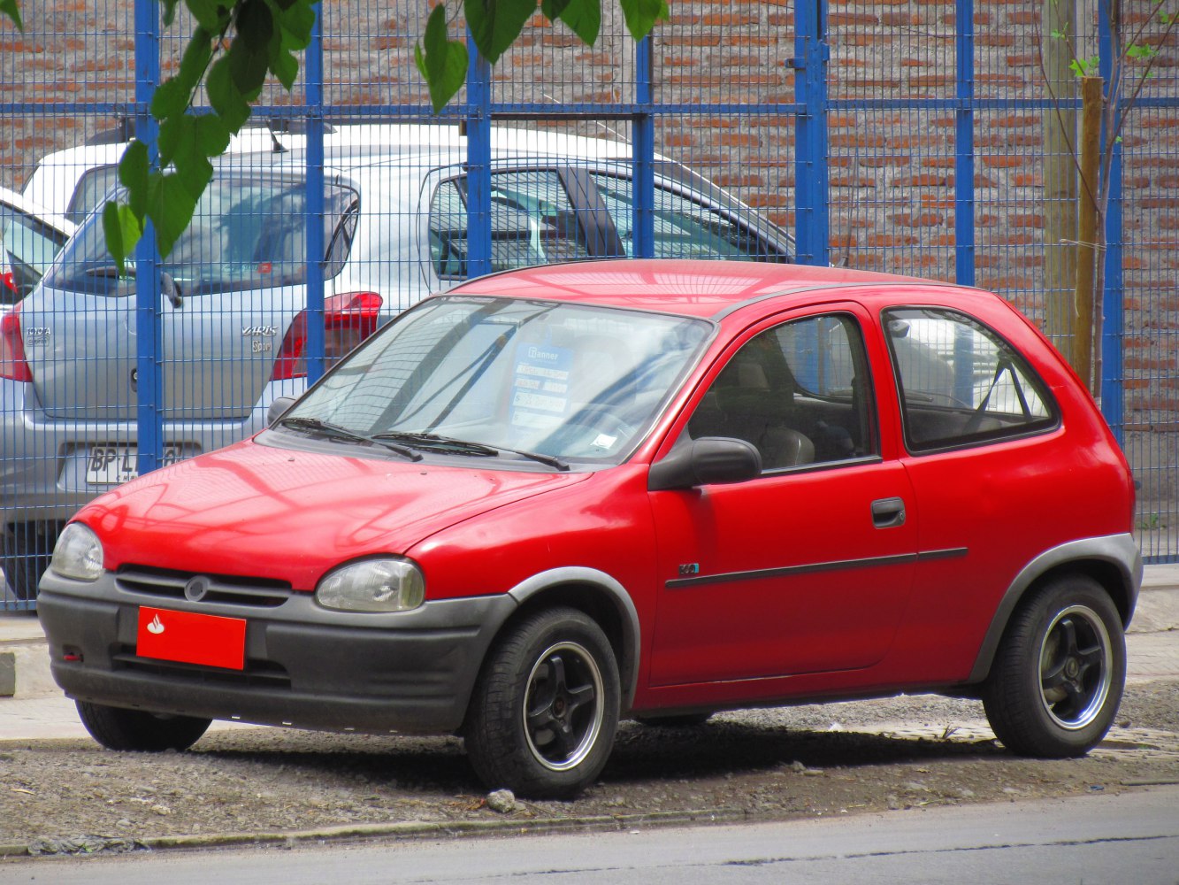 Red 3-door hatchback front side view with black bumpers and alloy wheels