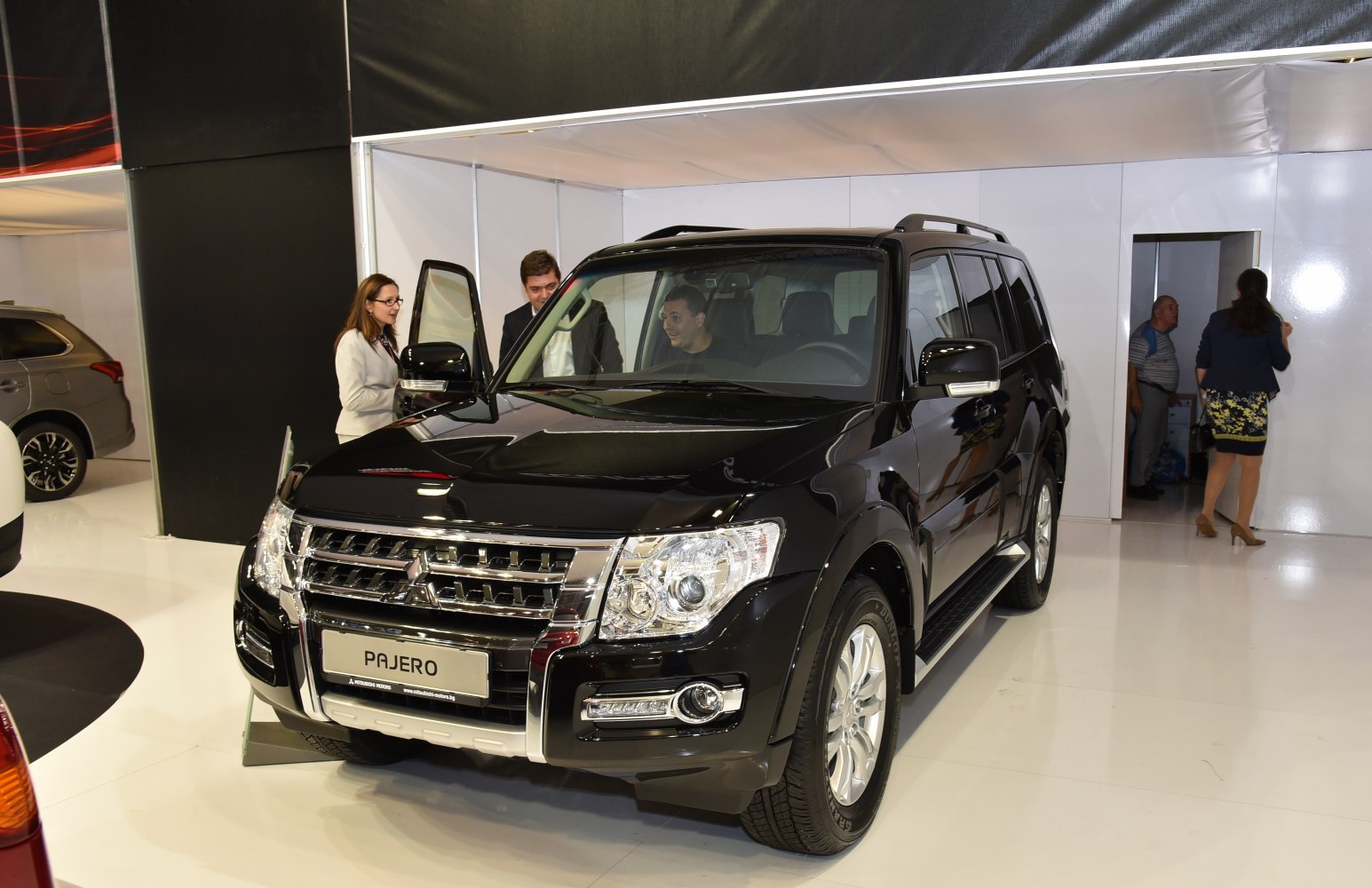 Black SUV with chrome grille and roof rails in showroom