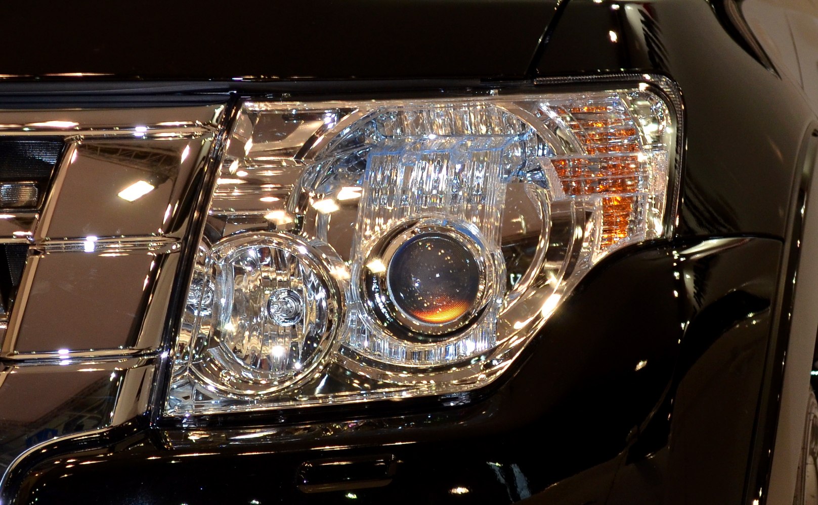 Close-up of a detailed multi-element car headlight with chrome surroundings