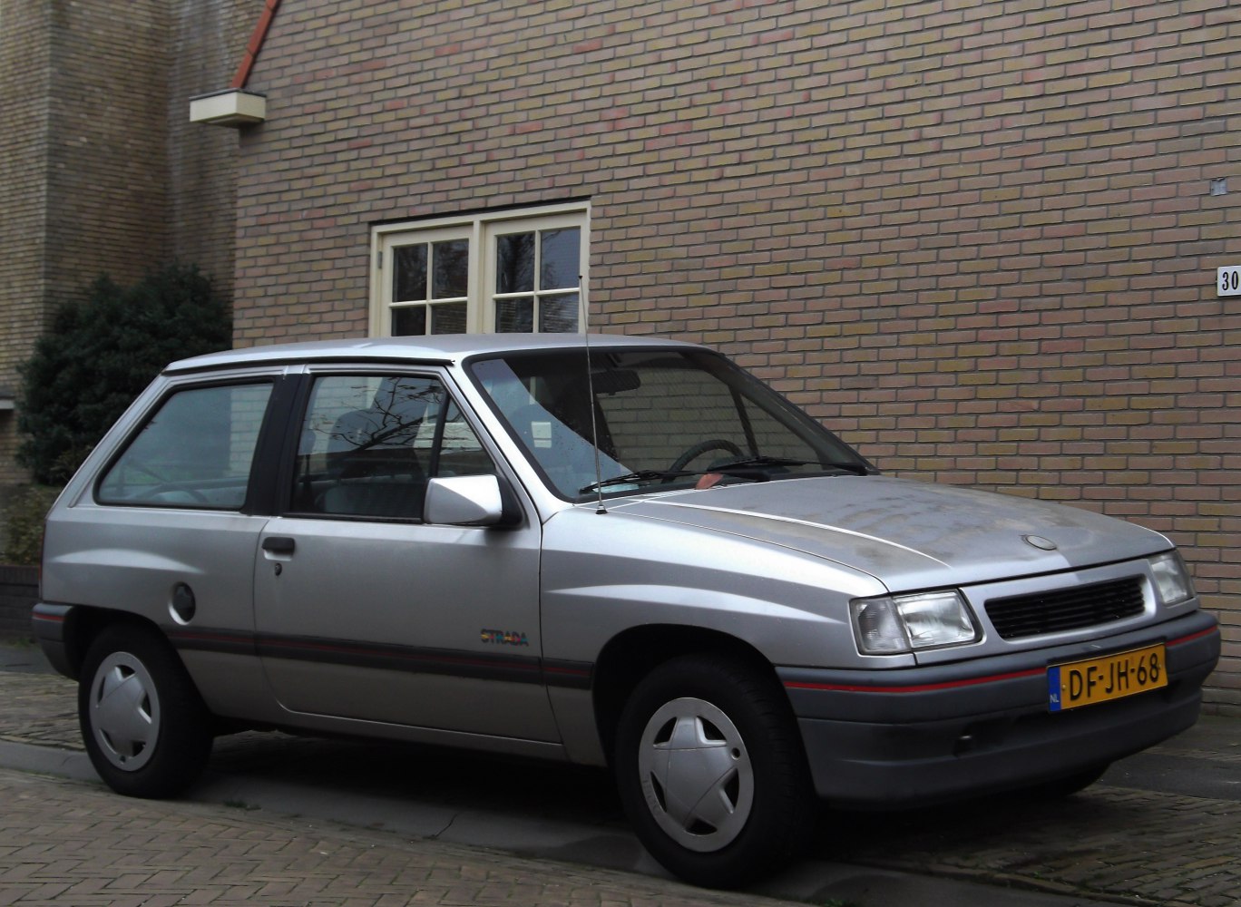 Silver compact hatchback side profile with three doors and antenna