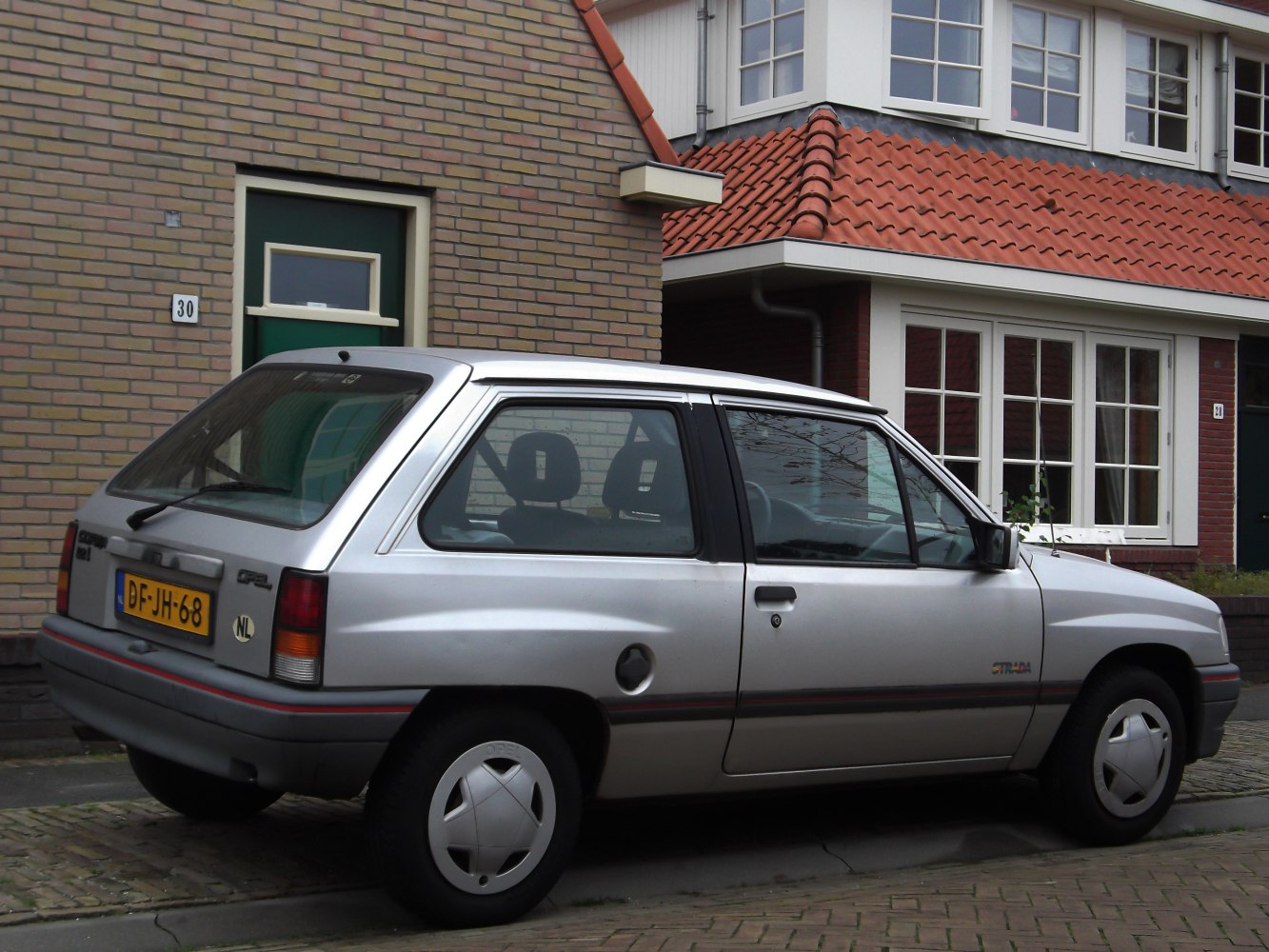 Silver 3-door hatchback side view with alloy wheels and red trim stripe