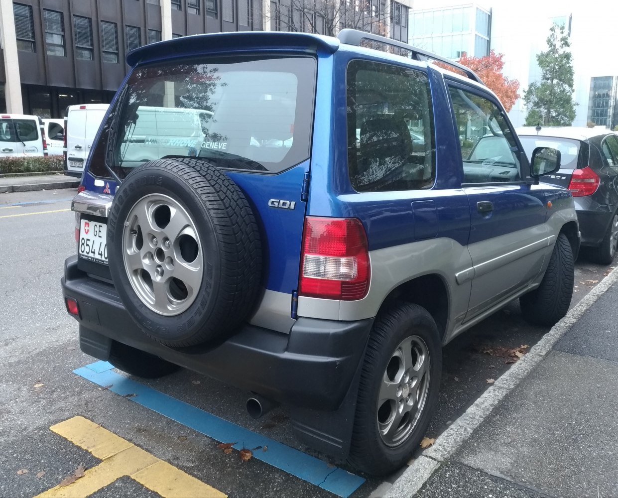 Rear side view with roof spoiler and mounted spare tire.