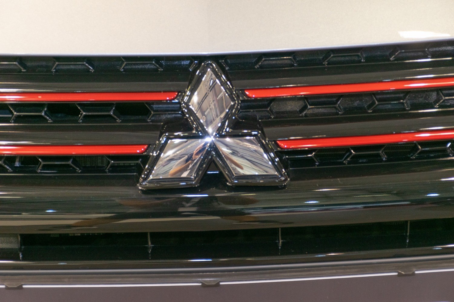 Close-up of front grille with Mitsubishi badge and red accent lines