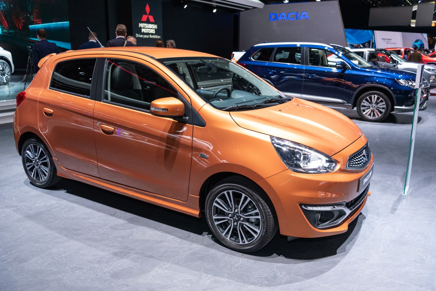 Orange hatchback with prominent headlights and alloy wheels front-side view