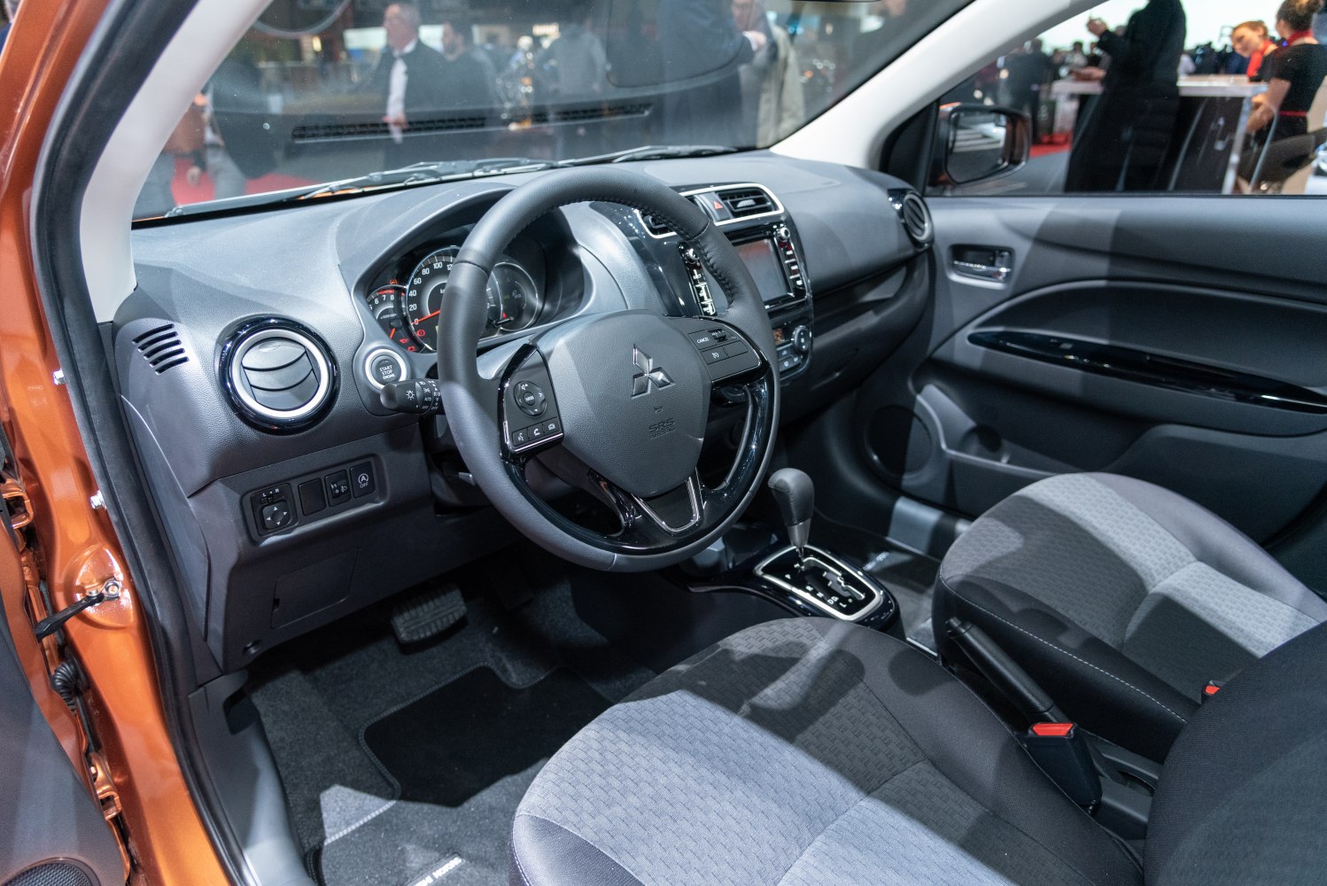 Compact car interior with dashboard, steering wheel, and gear shift.