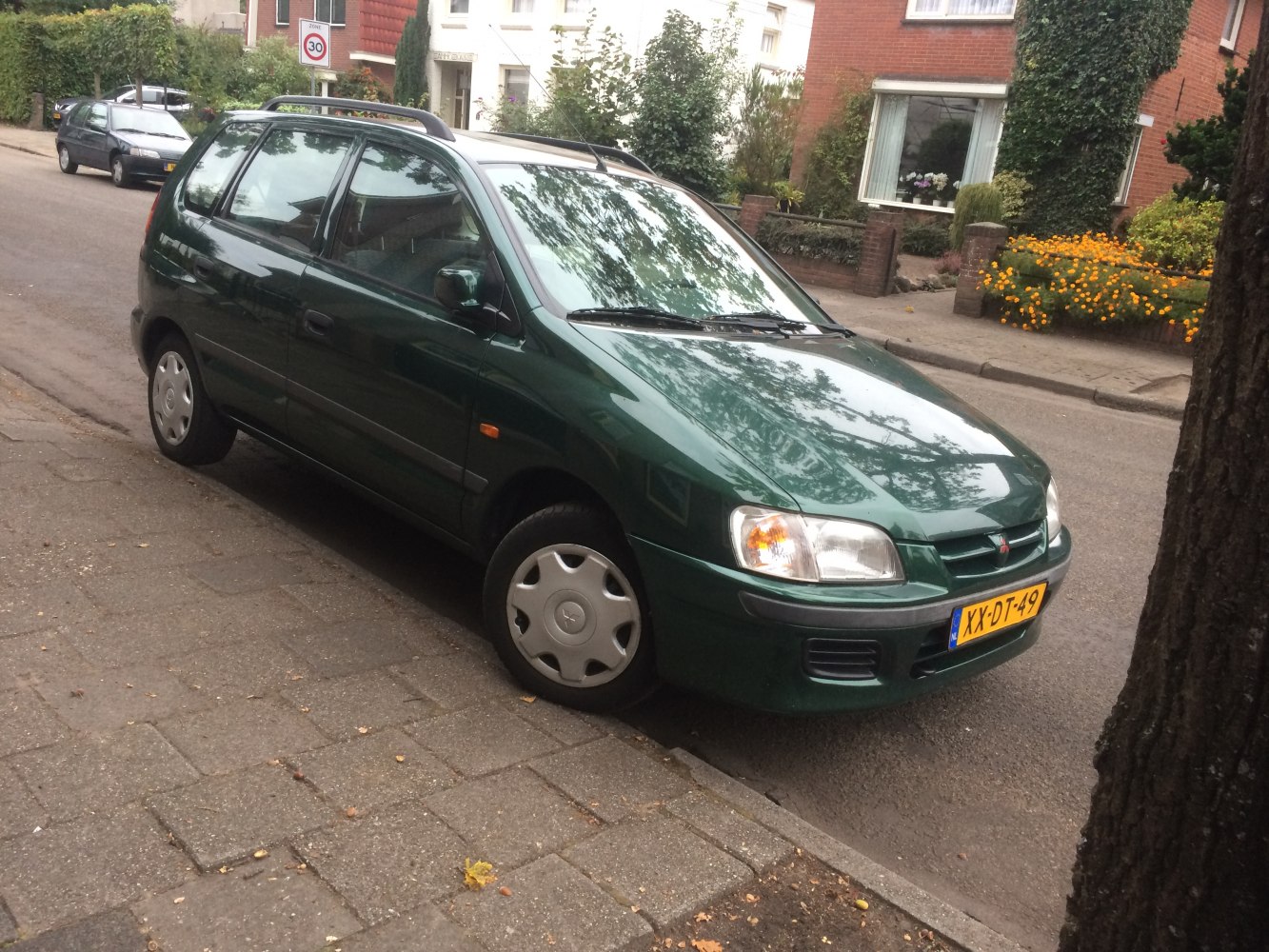 Compact MPV with roof rails and hubcaps parked on street