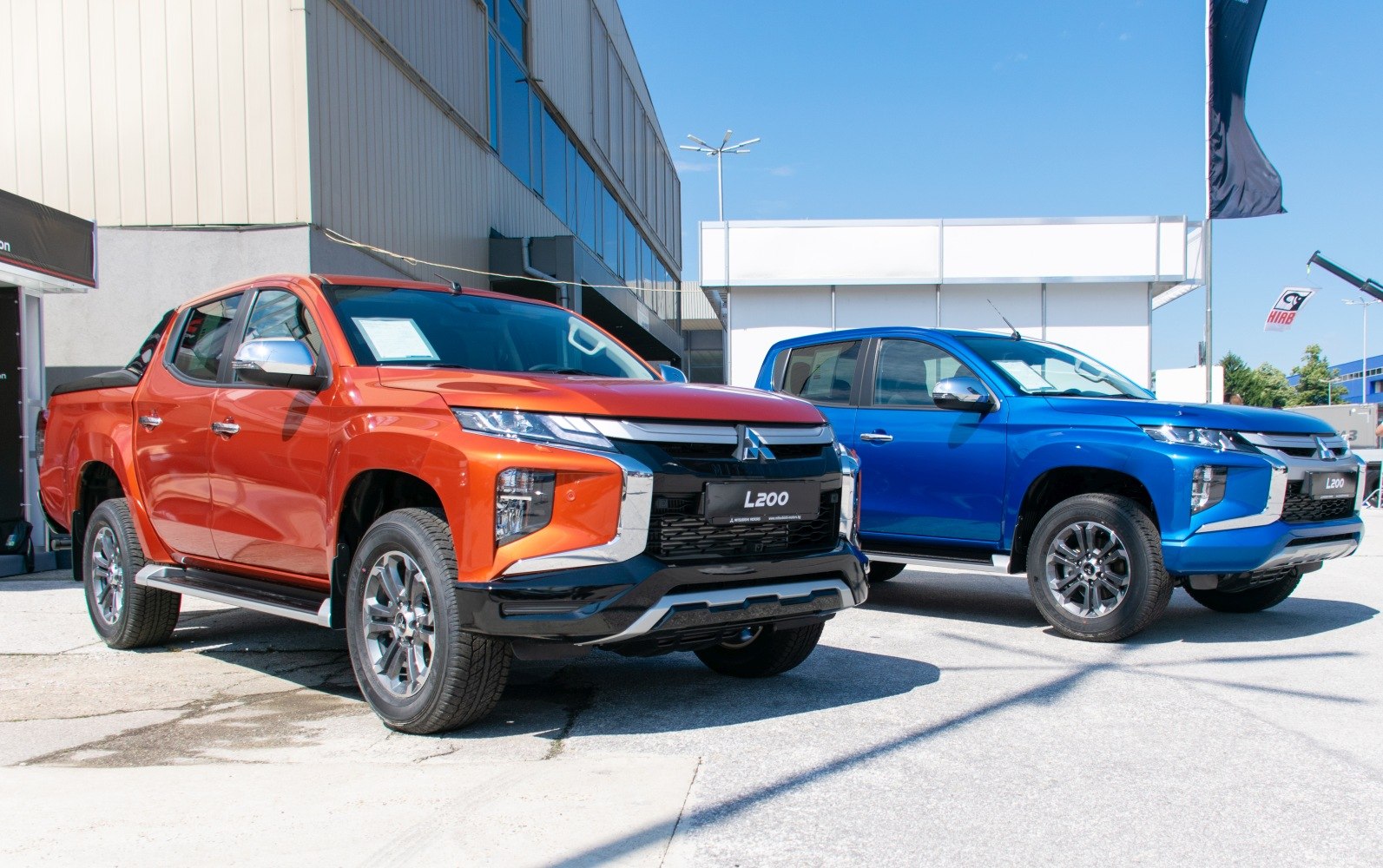 Front view of orange and blue double cab pickup trucks with bold grille and alloy wheels