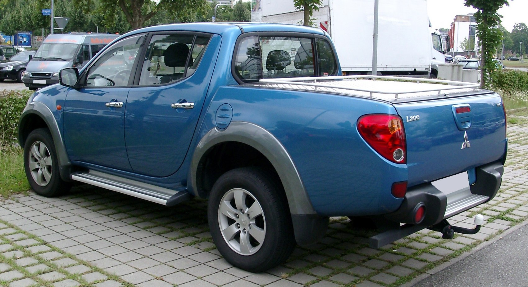 Blue pickup truck rear-side view with prominent wheel arches and side steps