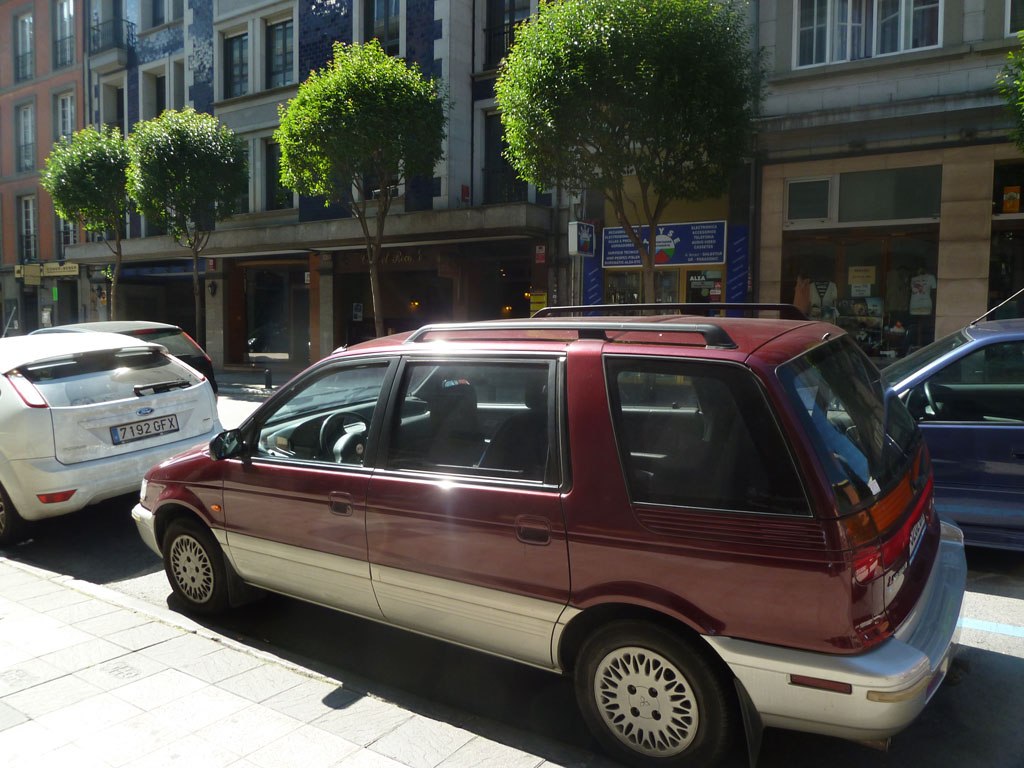 Side profile of a classic 1991 minivan with roof rails and distinct wheel design.