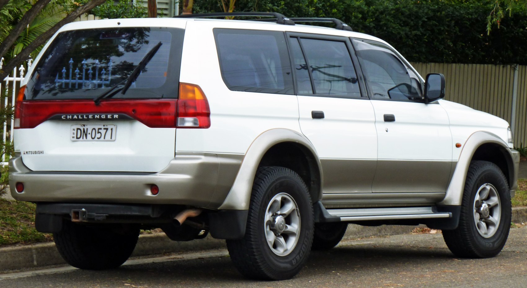 Rear and side view of white mid-1990s SUV with alloy wheels and rear wiper