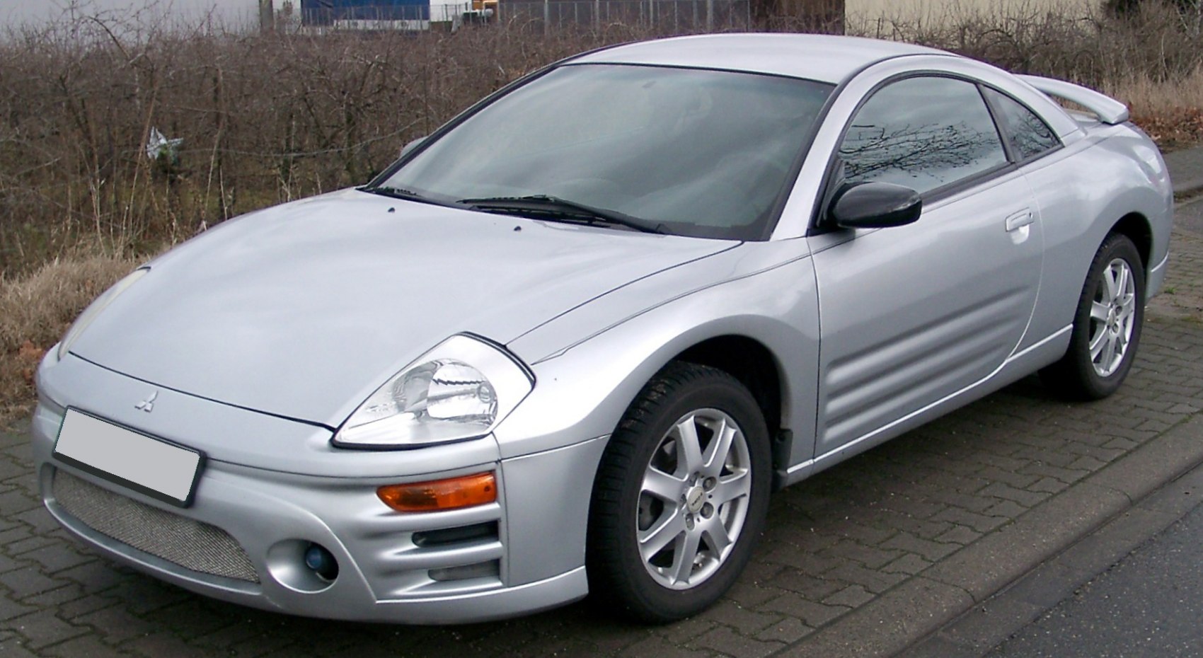 Front side view of silver sports coupe with alloy wheels and fog lights.