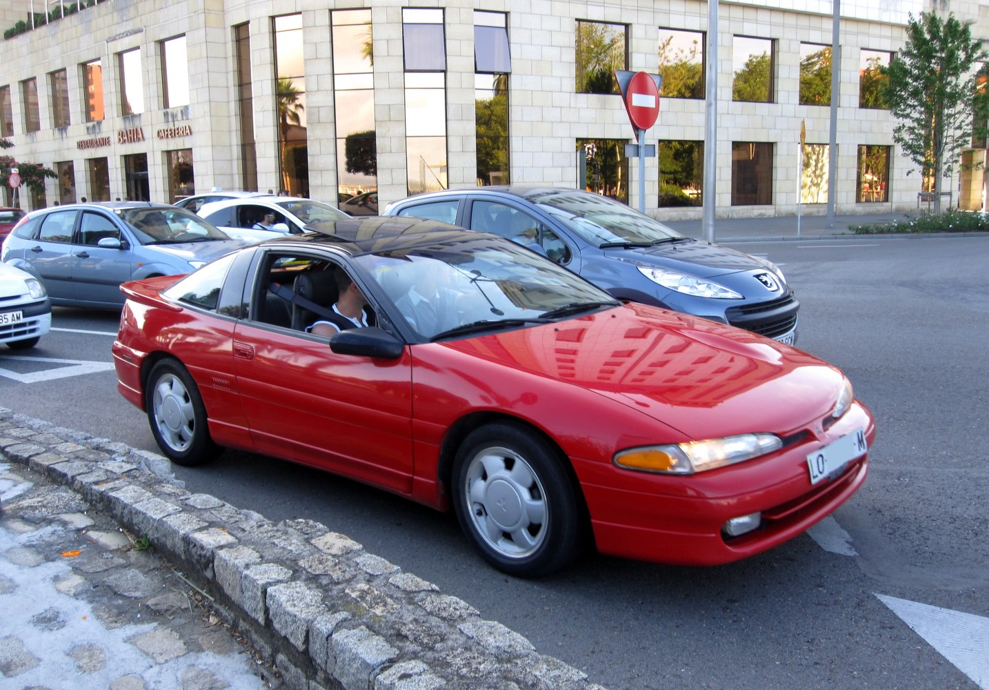 Bright red sporty coupe with sleek curved headlights parked on a city street.