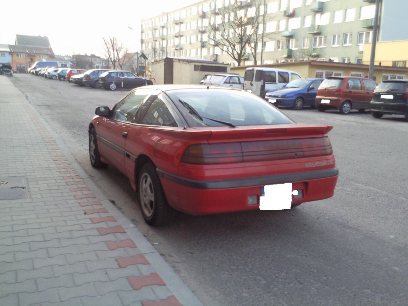 Rear view of red hatchback with rear spoiler and wraparound taillights