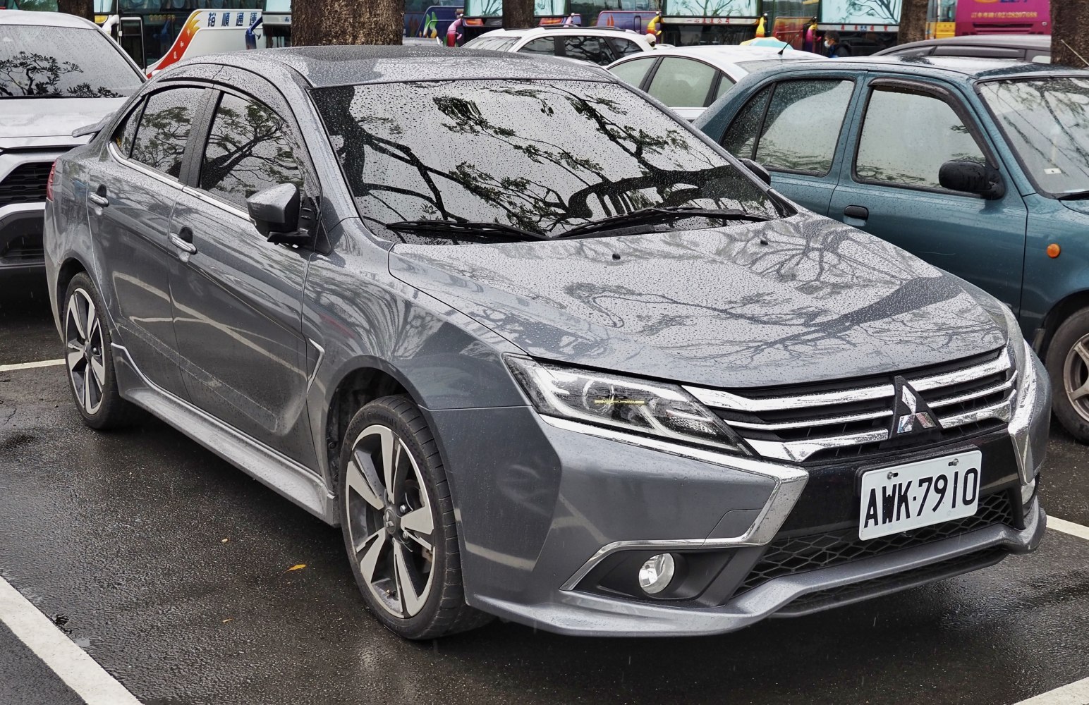 Front side view of sleek sedan with alloy wheels and rain droplets
