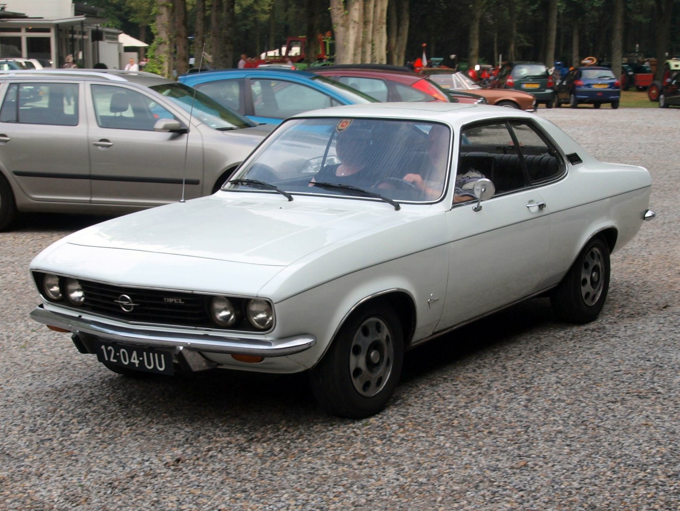 Vintage white coupe showing front profile with quad headlights and classic grille.