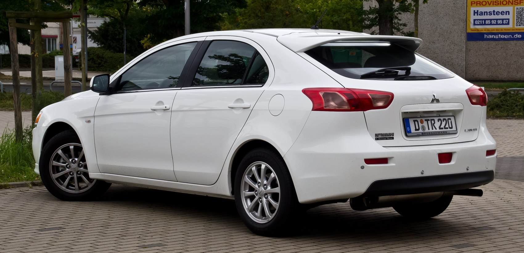 Rear-side profile of a white hatchback with sporty spoiler and alloy wheels