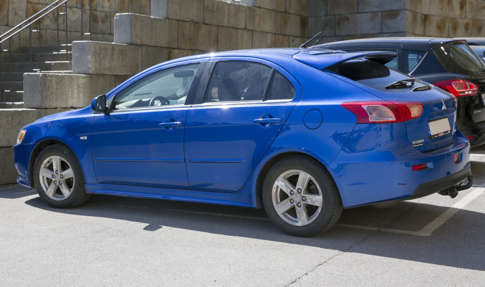 Side view of blue hatchback with alloy wheels and rear spoiler