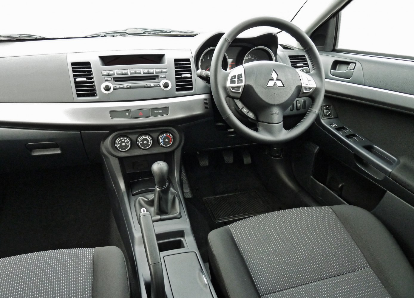Manual transmission gear shift and dashboard with steering wheel controls.