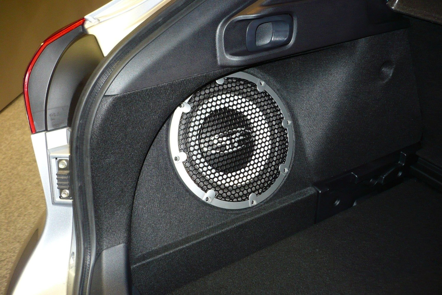 Subwoofer speaker with protective grille in car trunk interior